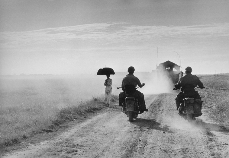 Dei motociclisti e una donna percorrono la strada da Nam Dinh a Thai Binh, Indocina (Vietnam), maggio 1954 © Robert Capa © International Center of Photography / Magnum Photos